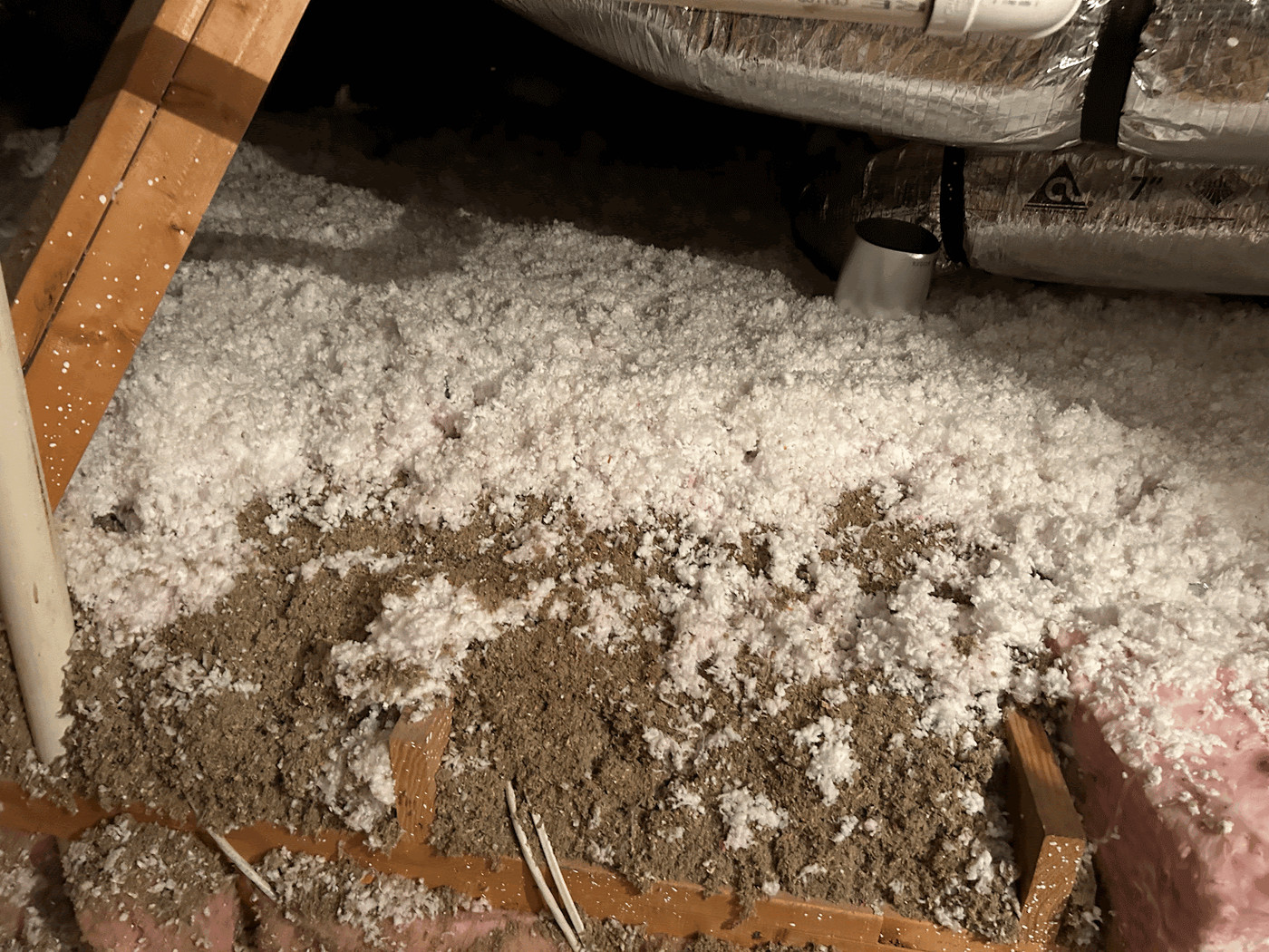 Multi-layered attic insulation, with dirty older material under newer blown-in fiberglass