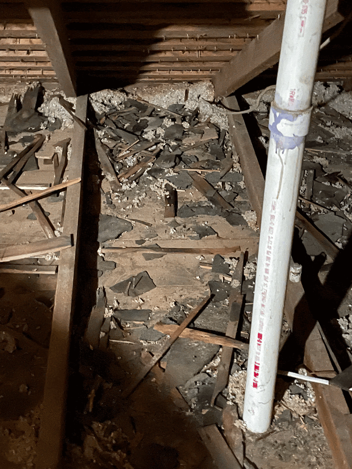 Cedar shake debris scattered across the attic deck after insulation removal