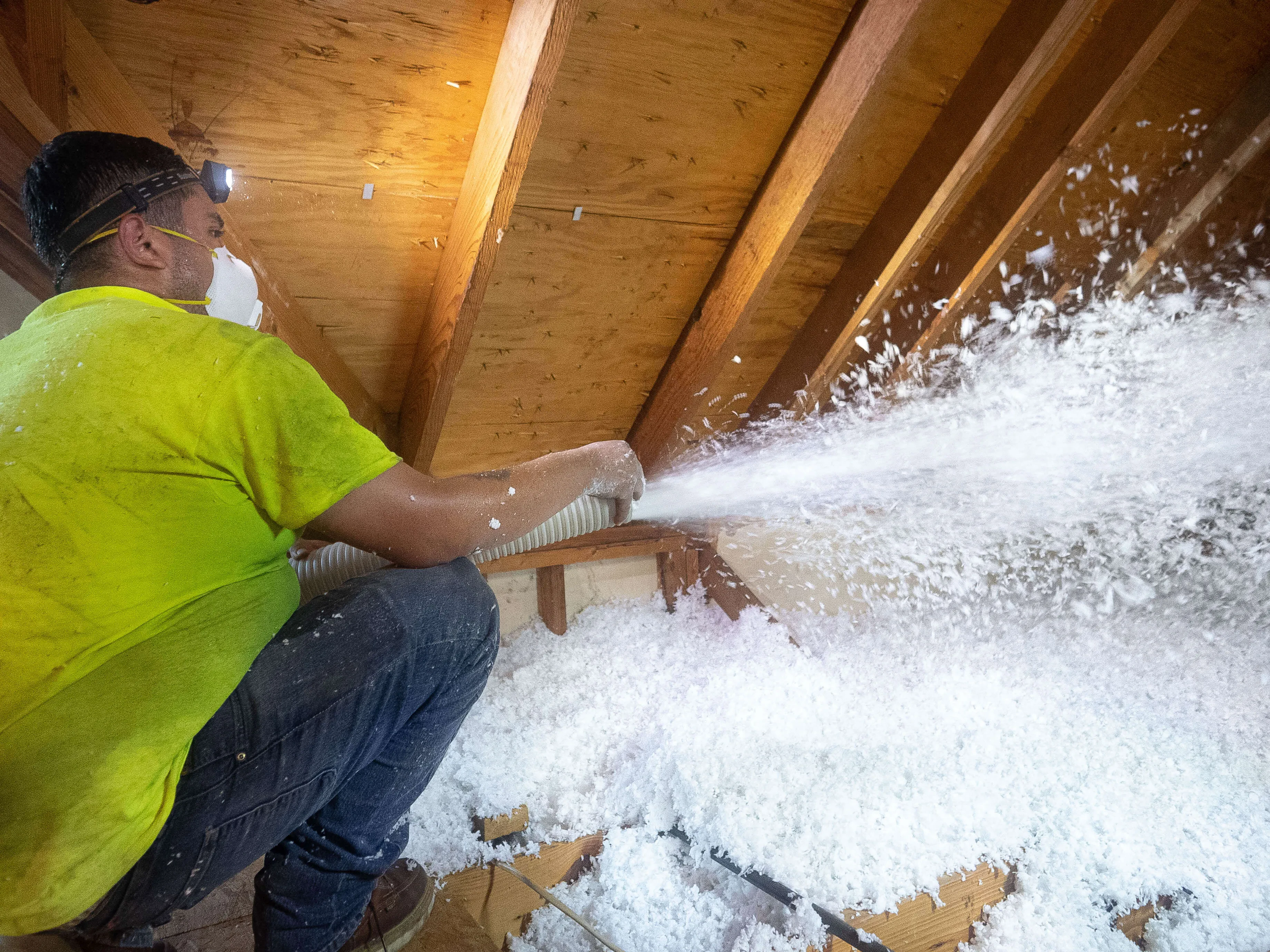 Technician blowing insulation into attic